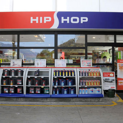 Zunanjost prodajalne HipShop z raznoliko ponudbo izdelkov in rdečo tablo HIP HOP.