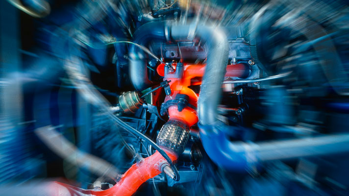 Na sliki je prikazan del avtomobilskega motorja v delovanju, kjer so nekateri deli zaradi visokih temperatur živo rdeče obarvani.