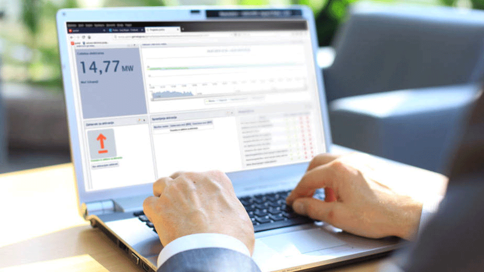 Slika prikazuje osebo, ki na prenosnem računalniku spremlja energetske podatke in analize o porabi električne energije.