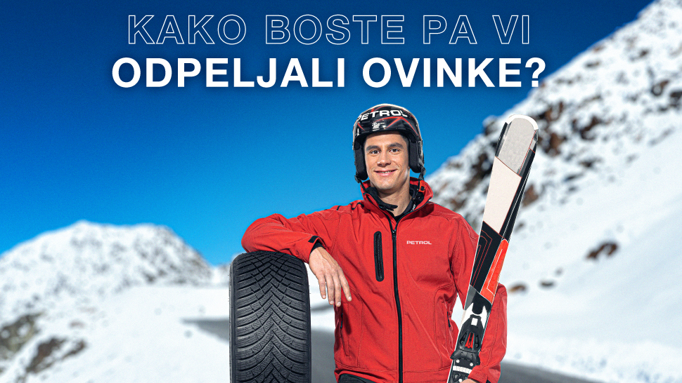 Moški v rdeči jakni in s čelado Petrol stoji na zasneženi gorski cesti. Naslonjen je na avtomobilsko gumo in v roki drži smuči. Na vrhu slike je napis: 'Kako boste pa vi odpeljali ovinke?'