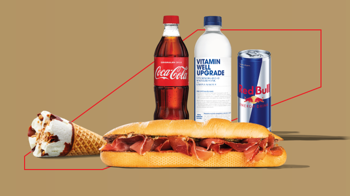 @Teja Hafner Kunšič alt opis: Na sliki so prikazani izdelki Coca-Cola, Vitamin Well Upgrade, Red Bull, sendvič s pršutom in sladoledni kornet, postavljeni na bež ozadju. V ozadju pa poteka rdeča geometrijska linija, ki vizualno poudarja izdelke.