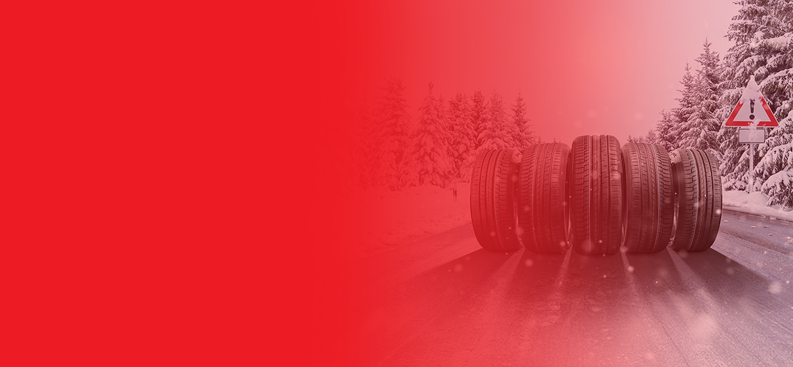Zimske pnevmatike, postavljene na zasneženi cesti v gozdu, z opozorilnim prometnim znakom in rdečim grafičnim prelivom v ozadju.