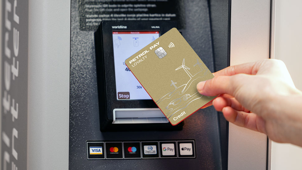 Na sliki je prikazano brezstično plačevanje z novo Petrol Pay Loyalty plačilno kartico Visa na polnilni postaji za električna vozila. Kartica je prislonjena k čitalniku na e-polnilnici, ki je opremljena z zaslonom in prikazuje podatke o polnjenju. Slika ponazarja možnost uporabe Petrol Pay Loyalty kartice za aktivacijo in plačilo polnjenja tako na Petrolovih kot tudi partnerskih e-polnilnicah.