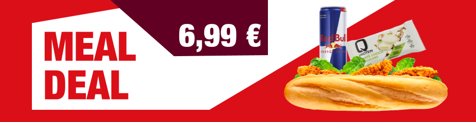 Reklamni banner z napisom »MEAL DEAL«. Na desni strani so prikazani izdelki iz ponudbe: sendvič z ocvrtim piščancem in solato, pločevinka energijske pijače Red Bull ter proteinska ploščica. Ozadje je v rdeči in beli barvi z geometrijskimi oblikami.