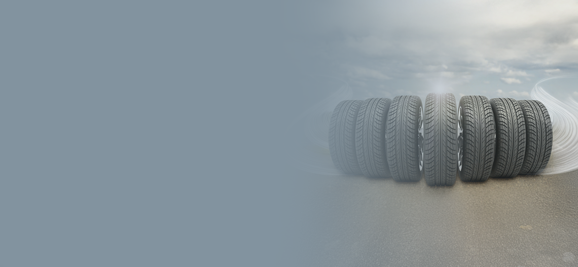 Vrsta avtomobilskih pnevmatik, postavljenih na cesti, z zamegljenim ozadjem in pogledom na zavito cesto.
