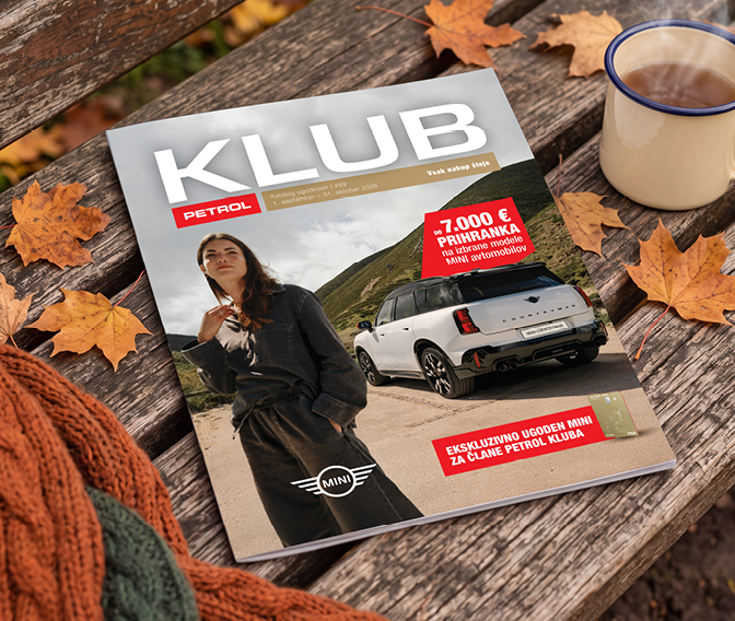 Na sliki je revija Petrol Klub, položena na leseno klop. Na naslovnici sta prikazana oseba in osebni avtomobil Mini Countryman, vidni pa so tudi napisi »KLUB«, »-7.000 € prihranka na izbrane modele MINI avtomobilov« in »Ekskluzivno ugoden MINI za člane Petrol Kluba«. Ob reviji stoji emajlirana skodelica z napitkom, okoli pa so raztreseni jesenski listi.