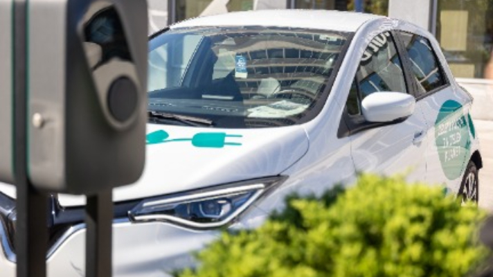 Električni avtomobil parkiran ob javni polnilnici za električna vozila.