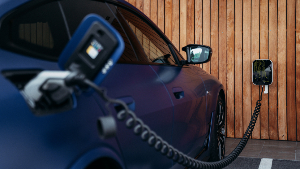 Električni avtomobil je priključen na domačo polnilnico ob leseni steni.
