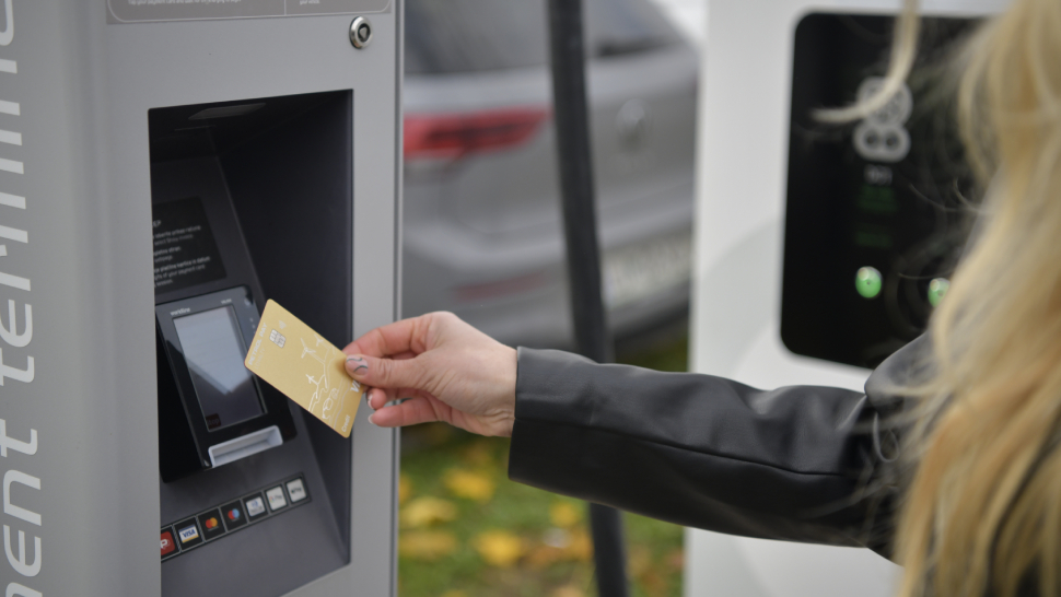 Oseba z zlato kartico plačuje na parkirnem avtomatu.