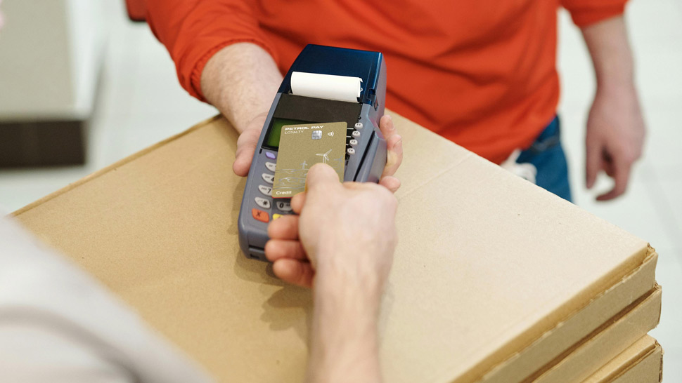 Oseba z zlato kartico plačuje na POS terminalu ob prevzemu paketa.