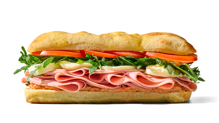 Na sliki je sendvič v focacci s tankimi rezinami mortadele, paradižnikom in listi rukole na beli podlagi.