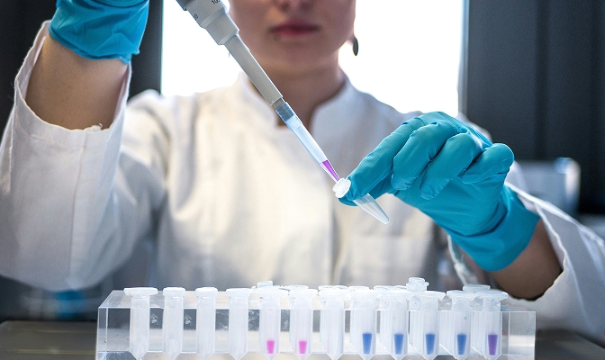 Laboratorijska analiza vzorcev s pipeto in epruvetami s tekočinami različnih barv.