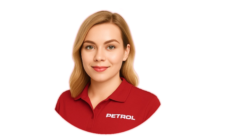 Na sliki je prikazana nasmejana virtualna asistentka z urejenimi, svetlo rjavimi lasmi do ramen. Oblečena je v rdečo polo majico z belim logotipom »PETROL«. Gleda naravnost v kamero, ima nežen izraz obraza in naraven videz, ozadje pa je svetlo in nevtralno.