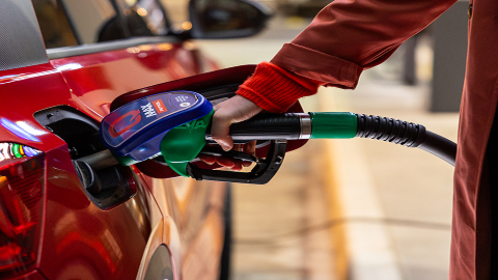 Roka drži točilno ročko Petrol Q Max med točenjem goriva v rdeč avtomobil.