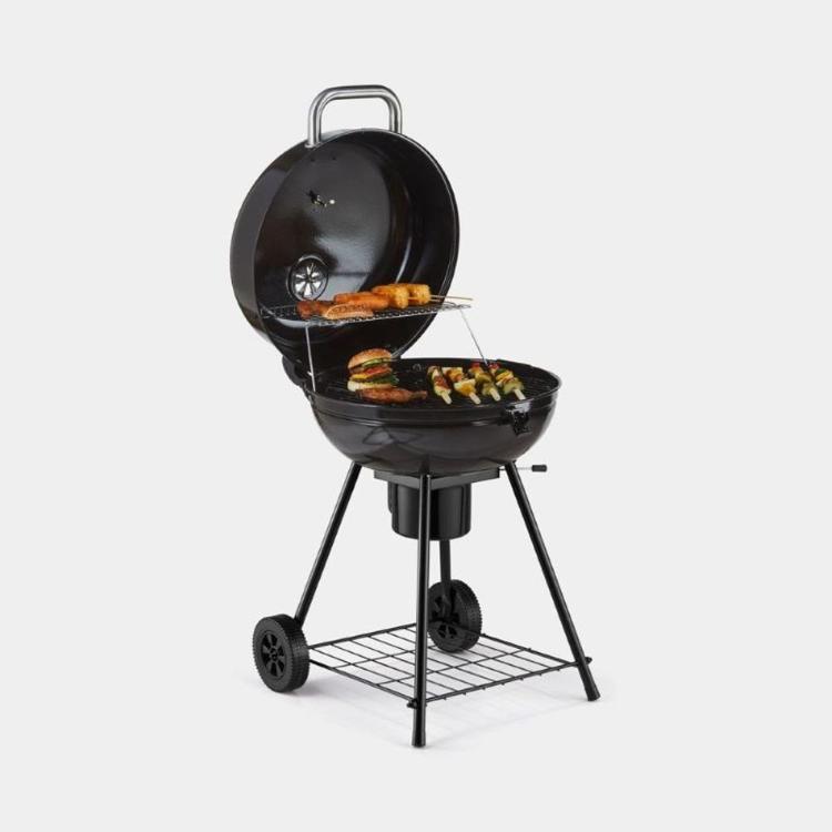  VonHaus Kettle BBQ v uporabi na terasi prikazuje prostorno površino za peko, dodatno ogrevalno rešetko in stabilno stojalo s kolesi, kar omogoča udobno pripravo hrane na prostem.