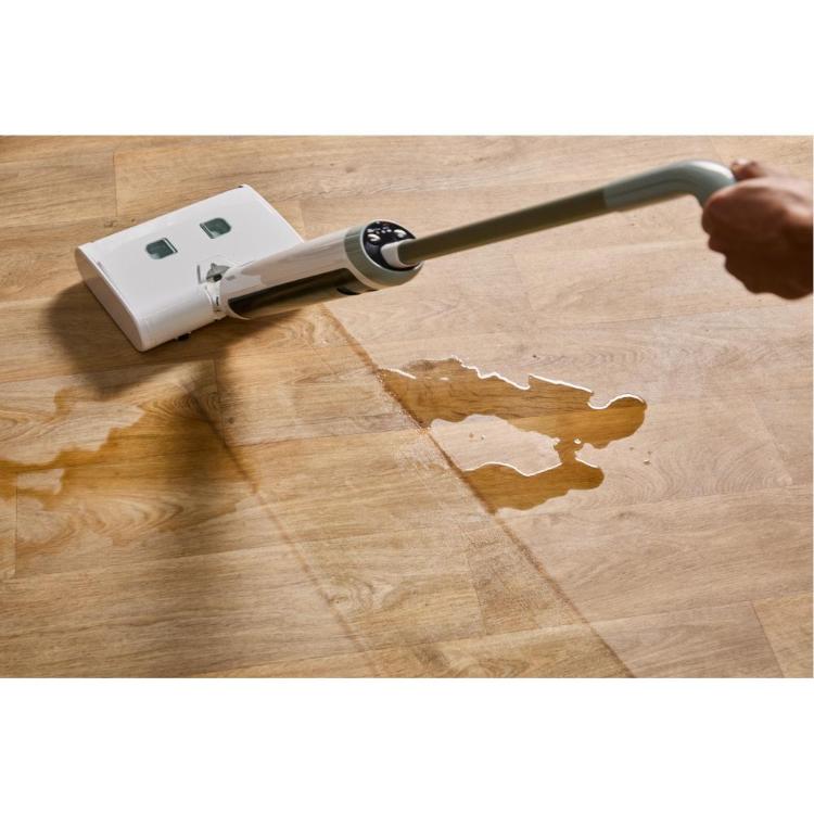 Rowenta X‑Wash čistilec tal v beli barvi, prikazan med pomivanjem razlite tekočine na lesenih tleh.