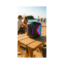 Prenosni zvočnik Blaunpunkt z RGB LED osvetlitvijo na leseni mizi na plaži, primeren za uporabo na prostem.