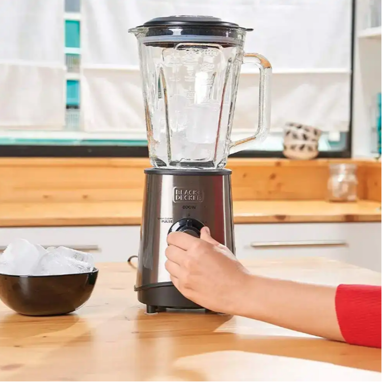 Black+Decker blender v uporabi na kuhinjskem pultu z ledenimi kockami v posodi, med nastavljanjem hitrosti z vrtljivim gumbom