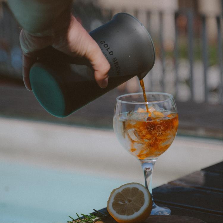 Goat Story Cold Brew, nalivanje hladne kave v kozarec z ledom, eleganten vrč v uporabi.