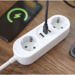 Bel podaljšek EMOS na leseni mizi, zaseden USB-C priključek polni pametni telefon v ozadju.