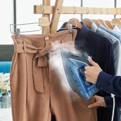 Rowenta parni likalnik v uporabi za navpično osveževanje in glajenje hlač na obešalniku z močnim izpustom pare