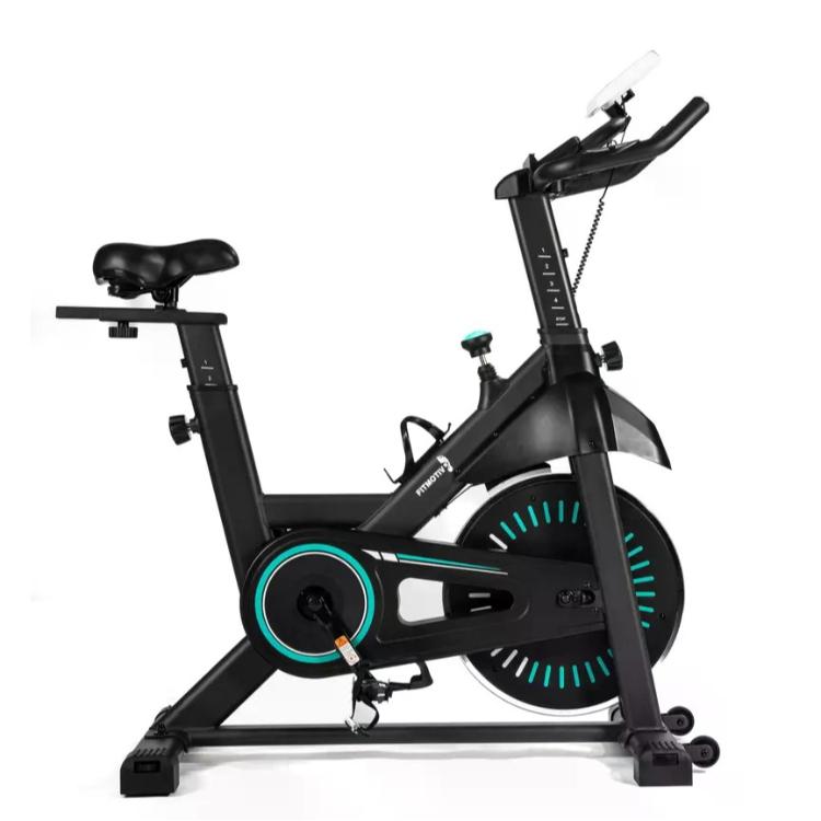Sobno kolo Fitmotiv Sprimer SB-50 v stranskem pogledu. Črn kovinski okvir z modrimi poudarki na vztrajniku in pogonskem ohišju, nastavljiv sedež ter krmilo z nosilcem za mobilno napravo. Vidna sta držalo za steklenico, transportna koleščka in športna pedala z varnostnimi trakovi.