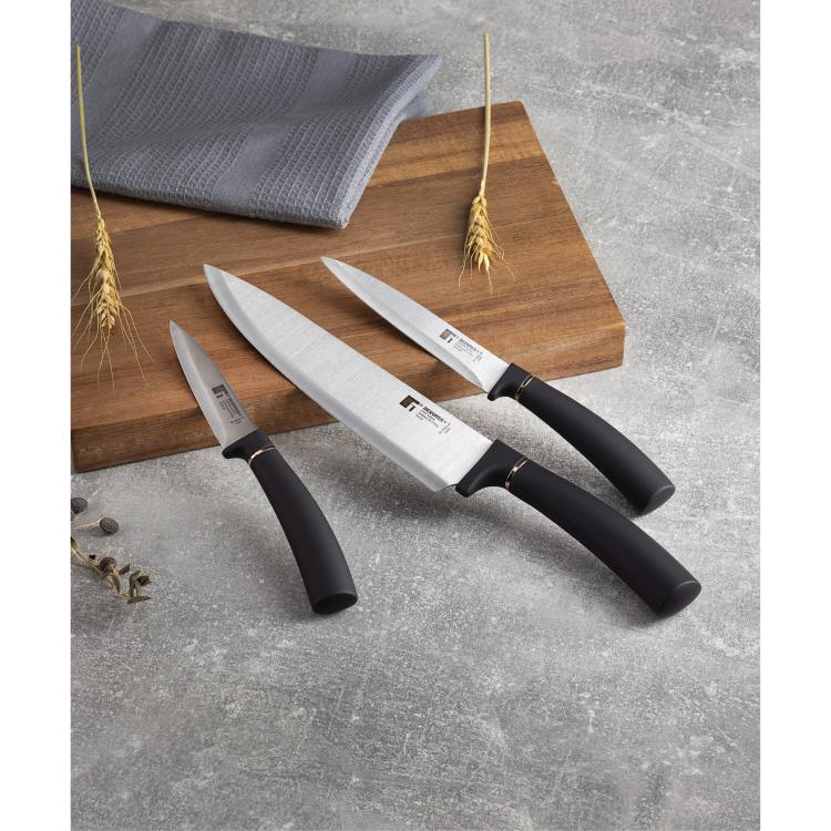 Kuhinjski noži Copper razporejeni na leseni deski v kuhinjskem ambientu.