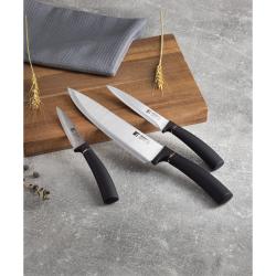 Kuhinjski noži Copper razporejeni na leseni deski v kuhinjskem ambientu.