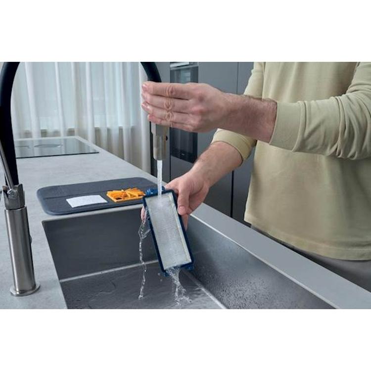 Pranje HEPA filtra sesalnika Hoover pod tekočo vodo za vzdrževanje čiste filtracije.