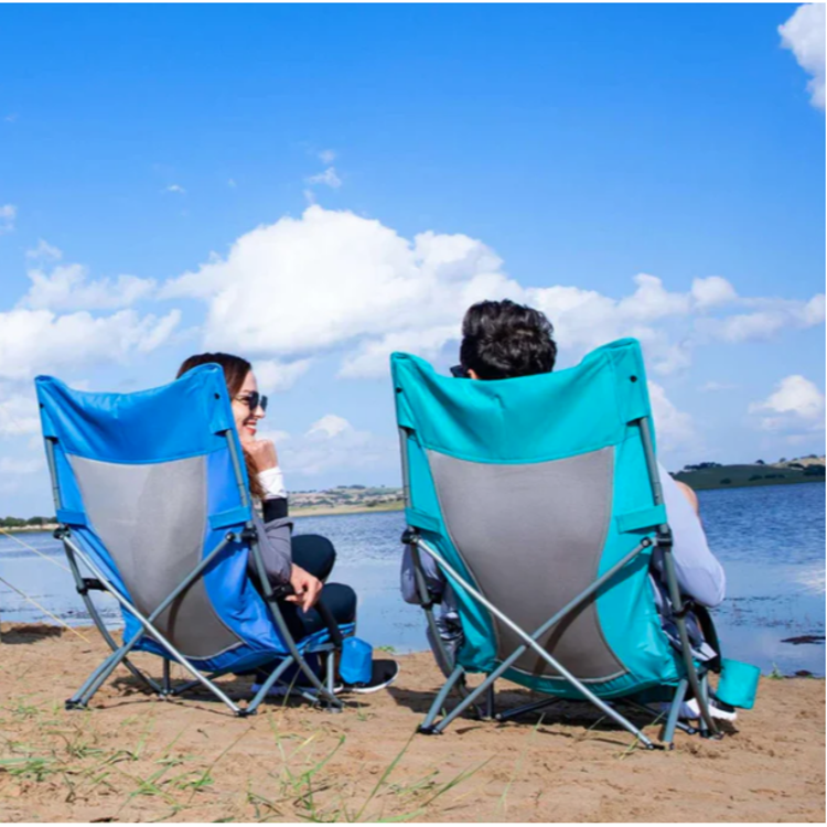 Dva nizka kamping stola KingCamp v uporabi ob vodi, primerna za kampiranje in sprostitev na prostem.