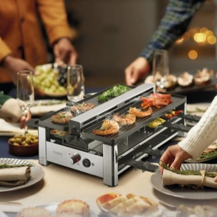 Raclette žar CASO Design z vgrajenim sistemom odvajanja pare in vonjav, dvema rebrastima ploščama za peko ter osmimi posodicami omogoča prijetno druženje in pripravo različnih jedi neposredno za mizo.