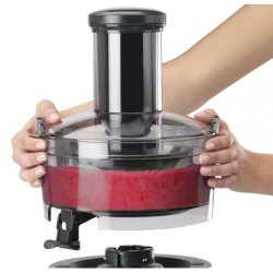 Osebi držita zgornji del Nutribullet Juicer Pro sokovnika z vidno rdečo pulpo v prozorni posodi
