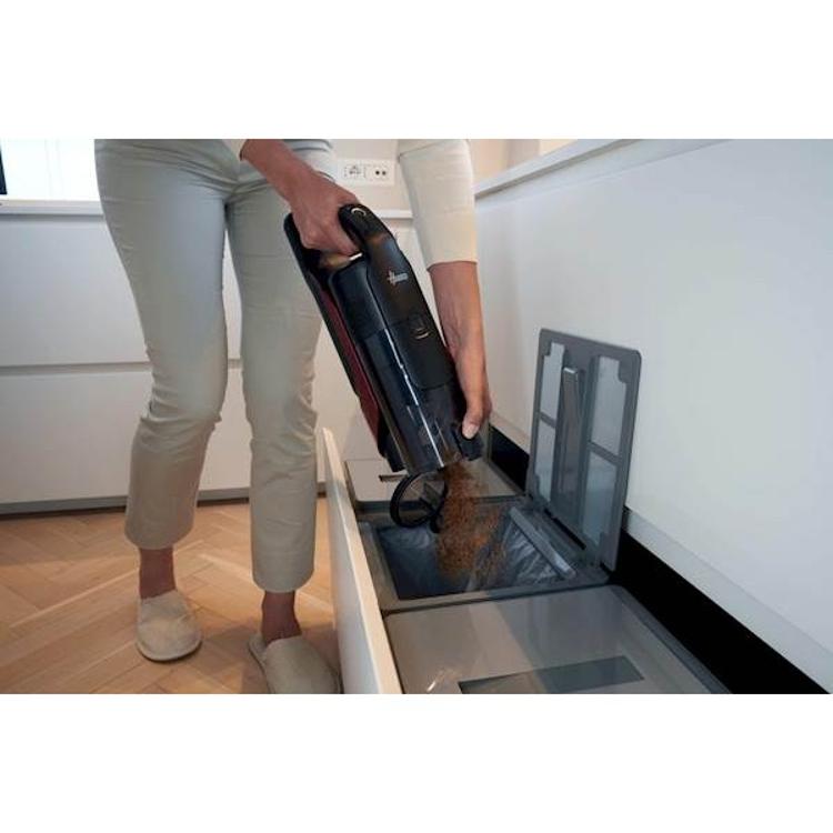 Praznjenje posode za prah baterijskega sesalnika Hoover neposredno v koš.