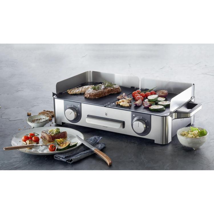 WMF Lono Master Grill namizni žar z dvema conama, na katerem se pečejo meso (zrezek, piščanec) in zelenjava (paradižniki, bučke, čebula)