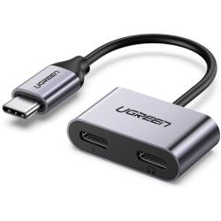 Kompakten USB-C adapter z dvema USB-C priključkoma za hkratno polnjenje in uporabo slušalk.