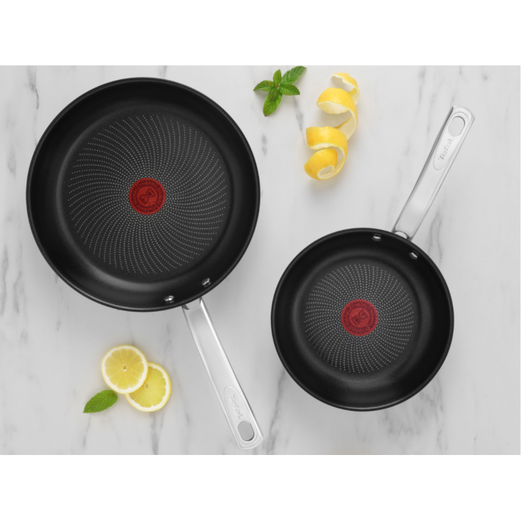 Tefal set dveh ponev z nelepljivo površino, Thermo‑Signal indikatorjem na sredini in inox ročaji, postavljen na svetli marmorni podlagi z limono in meto