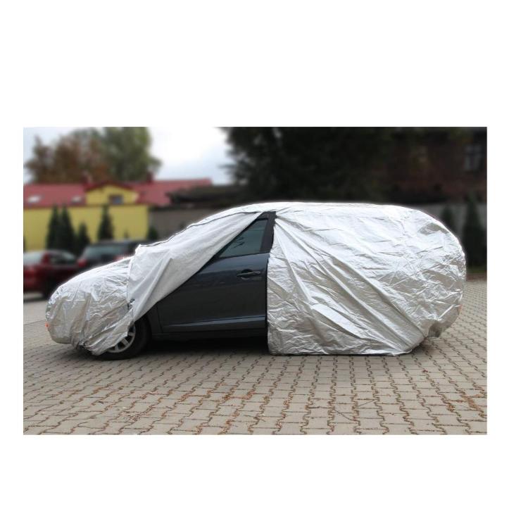 Siv avto delno odkrit; zadnji del pokrit, spredaj vidna vrata, okno in kolo na tlakovcih.